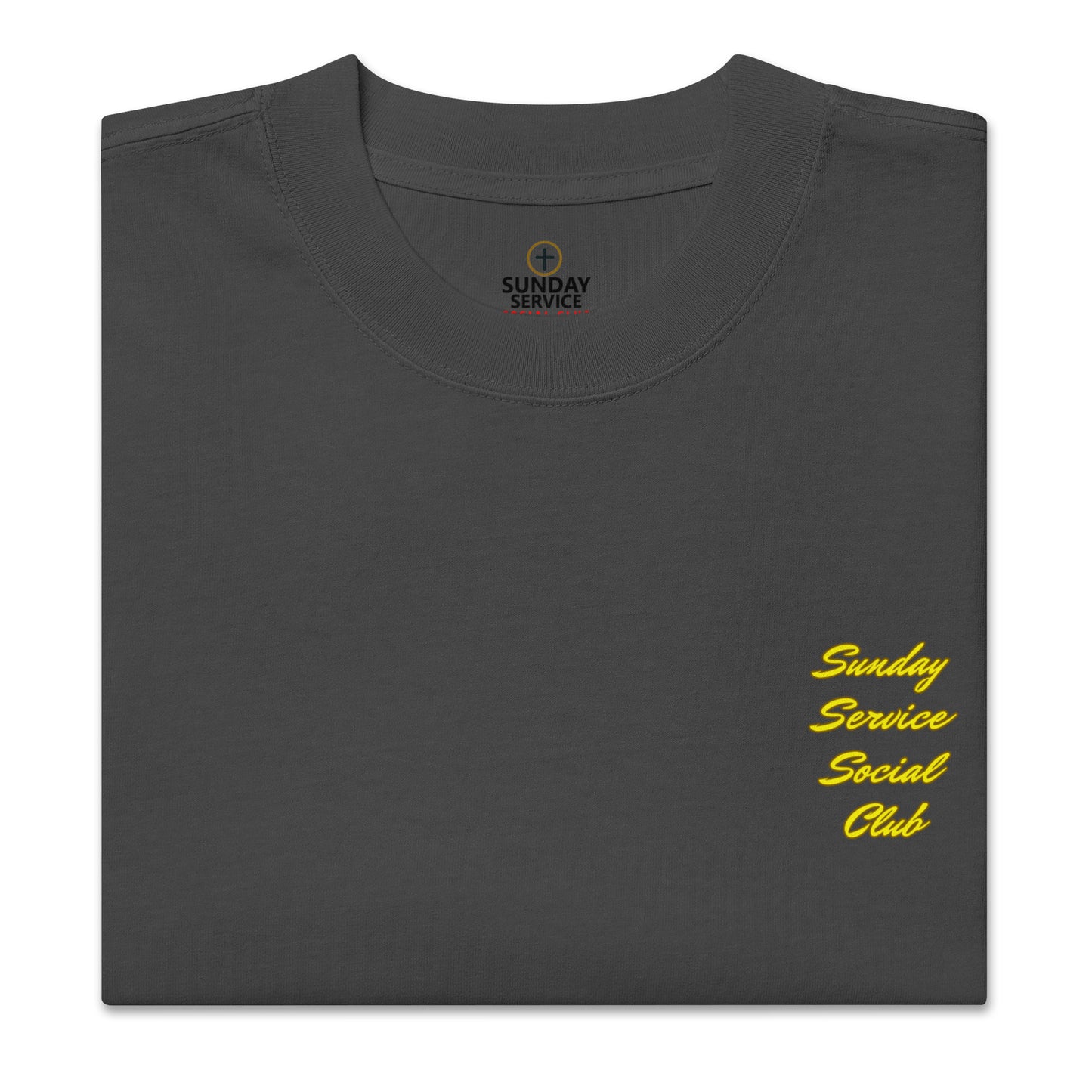 Front of a black t-shirt with the words 'Sunday Service Social Club' printed in large, bold, yellow cursive font. The text is stacked vertically in four lines, creating a vibrant and eye-catching design against the black background.